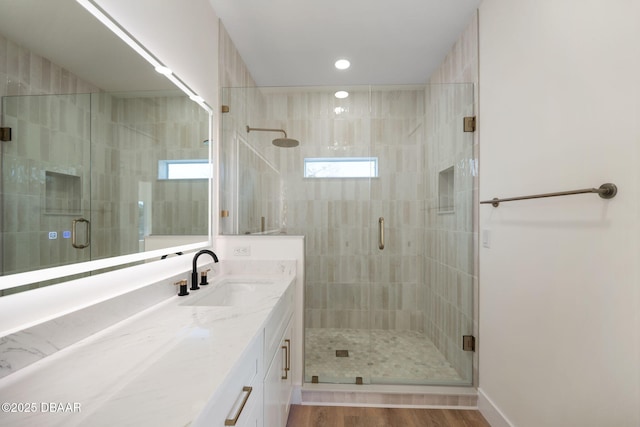 bathroom with walk in shower, vanity, and wood-type flooring