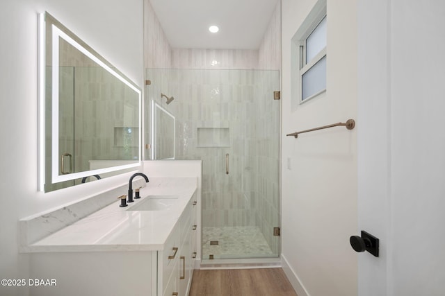 bathroom featuring walk in shower, vanity, and wood-type flooring