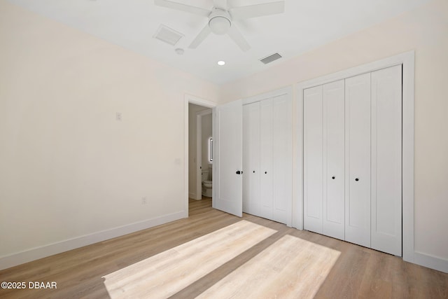 unfurnished bedroom featuring multiple closets, ceiling fan, and light hardwood / wood-style flooring