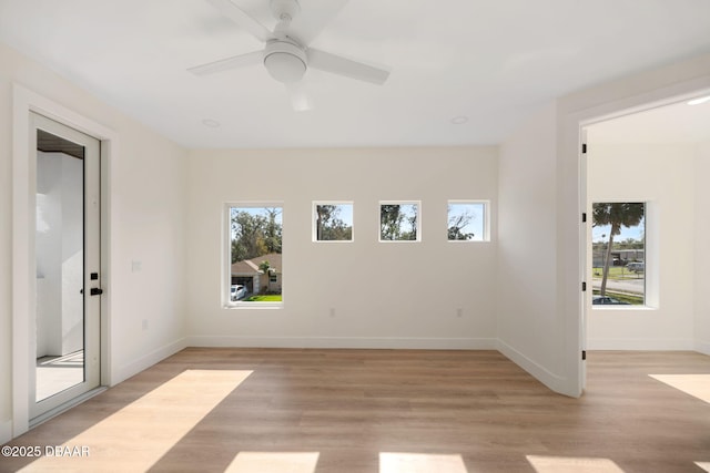 empty room featuring a wealth of natural light, ceiling fan, and light wood-type flooring