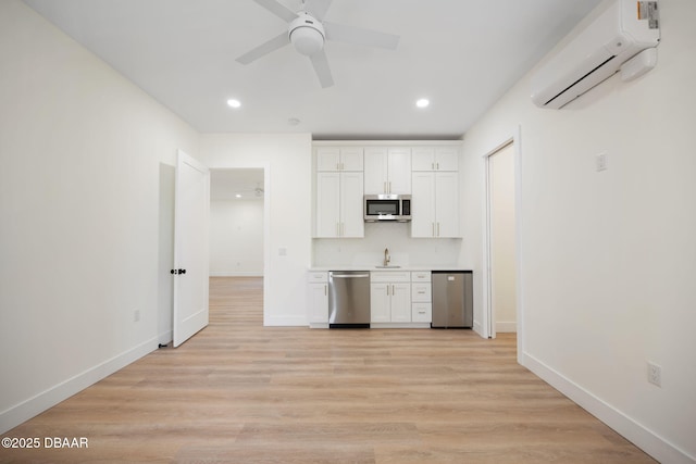 kitchen featuring light hardwood / wood-style flooring, ceiling fan, appliances with stainless steel finishes, white cabinetry, and a wall mounted AC