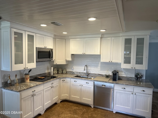 kitchen featuring appliances with stainless steel finishes, white cabinetry, sink, dark stone countertops, and crown molding