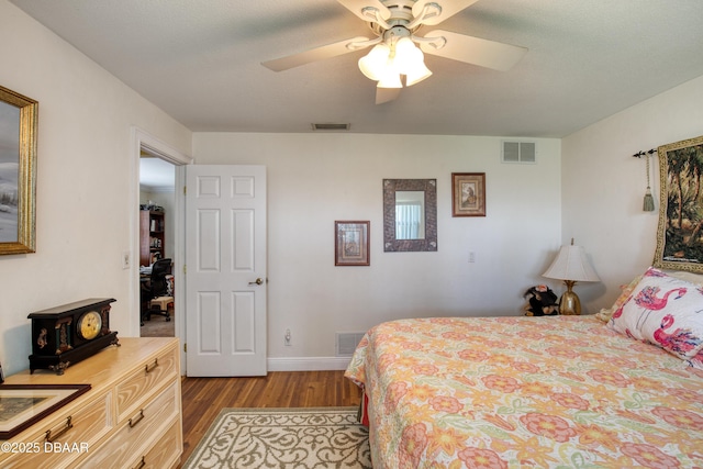 bedroom featuring a wood stove, ceiling fan, and light wood-type flooring