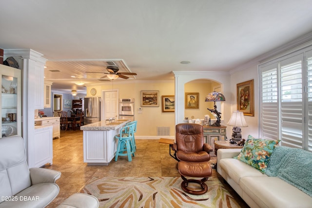 tiled living room featuring crown molding, ceiling fan, and ornate columns