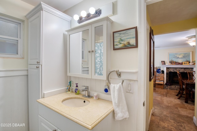 bathroom featuring stone finish flooring, a brick fireplace, and vanity