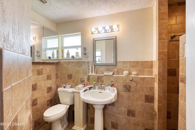 bathroom with tile walls, a textured ceiling, and toilet