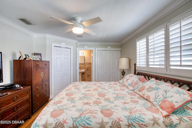 bedroom featuring ceiling fan, ornamental molding, ensuite bath, and a textured ceiling