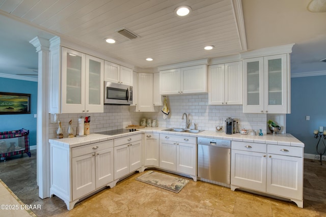 kitchen with appliances with stainless steel finishes, tasteful backsplash, sink, white cabinets, and crown molding