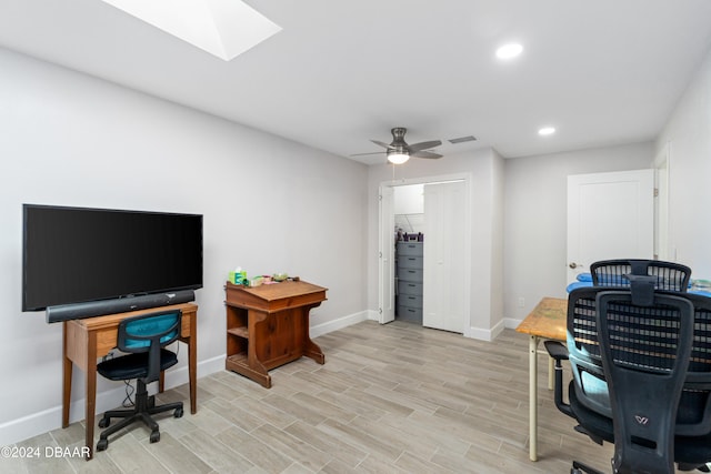 office with a skylight, light hardwood / wood-style floors, and ceiling fan