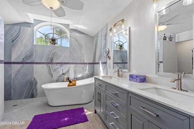 bathroom with a tub, ceiling fan, hardwood / wood-style floors, vaulted ceiling, and tile walls