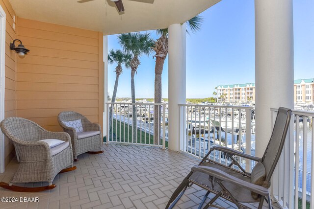 balcony featuring a water view and ceiling fan