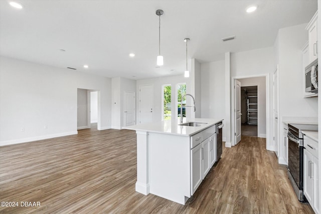 kitchen featuring light hardwood / wood-style floors, sink, appliances with stainless steel finishes, an island with sink, and white cabinets