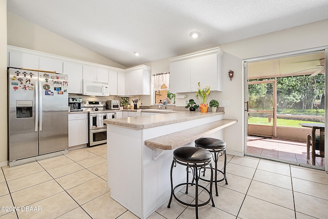 kitchen with white cabinetry, light tile patterned floors, stainless steel appliances, and vaulted ceiling