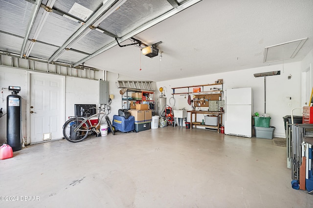 garage with electric panel, white fridge, and a garage door opener