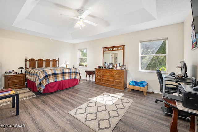 bedroom with a raised ceiling, ceiling fan, dark hardwood / wood-style flooring, and a textured ceiling