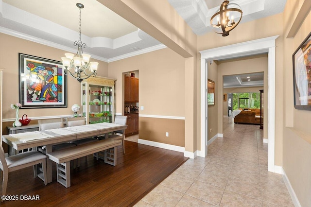 612 Aldenham Ln, Ormond Beach, FL 32174 - dining space with a chandelier, a raised ceiling, ornamental molding, baseboards, and light tile patterned floors