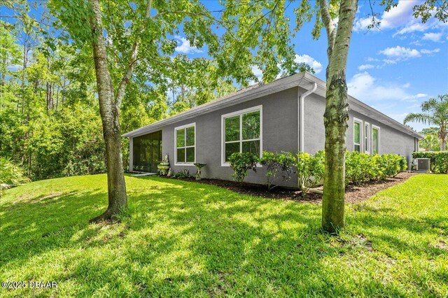 612 Aldenham Ln, Ormond Beach, FL 32174 - view of home's exterior with stucco siding, a lawn, and central AC