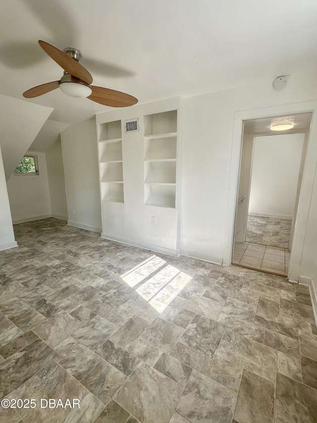 1011 S Peninsula Dr, Daytona Beach, FL 32118 - empty room with ceiling fan, stone finish flooring, built in shelves, and baseboards