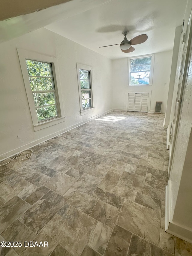 1011 S Peninsula Dr, Daytona Beach, FL 32118 - unfurnished room with healthy amount of natural light, a ceiling fan, stone finish flooring, and baseboards