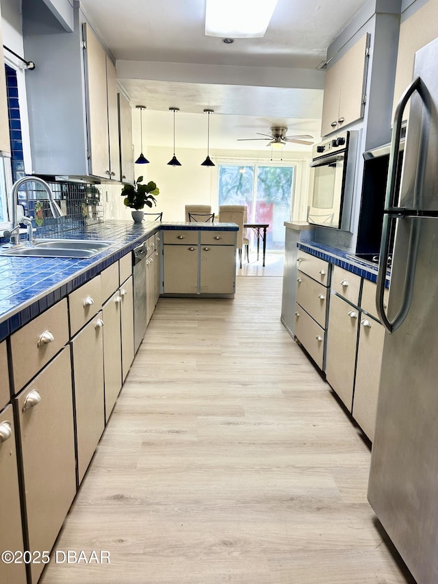 1011 S Peninsula Dr, Daytona Beach, FL 32118 - kitchen featuring appliances with stainless steel finishes, a sink, tile counters, and light wood-type flooring