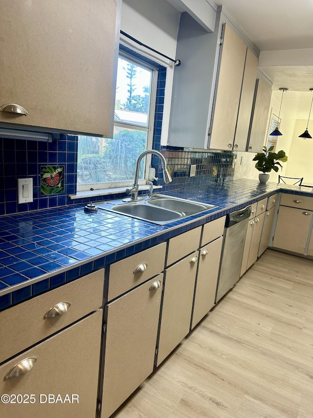1011 S Peninsula Dr, Daytona Beach, FL 32118 - kitchen featuring a sink, dishwasher, tile countertops, light wood-style flooring, and decorative backsplash