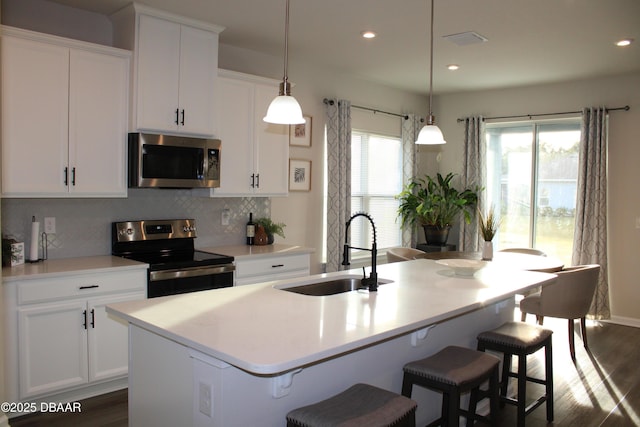 kitchen featuring sink, decorative light fixtures, appliances with stainless steel finishes, a kitchen island with sink, and backsplash