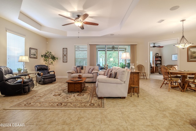 living room with ceiling fan and a tray ceiling