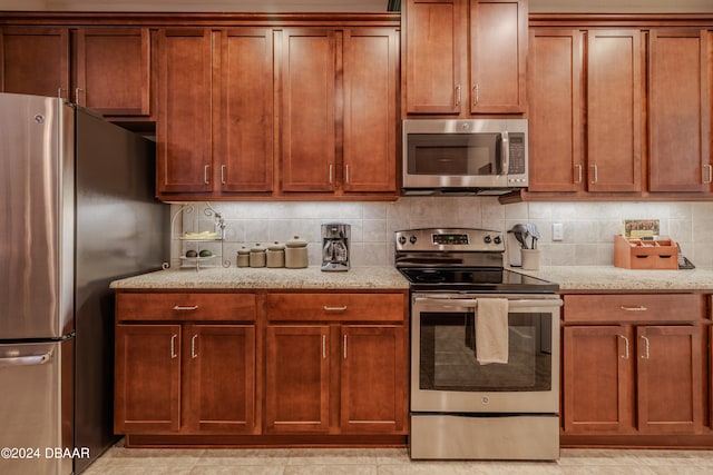 kitchen featuring light stone countertops, light tile patterned floors, backsplash, and appliances with stainless steel finishes