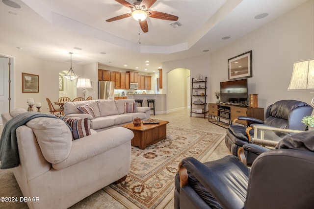 living room featuring ceiling fan and a tray ceiling