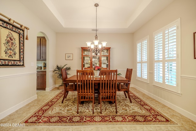 dining area with an inviting chandelier and a tray ceiling