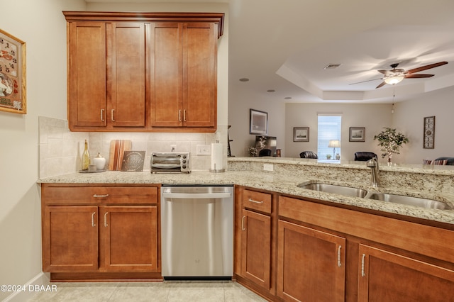 kitchen featuring dishwasher, sink, light stone counters, and a raised ceiling