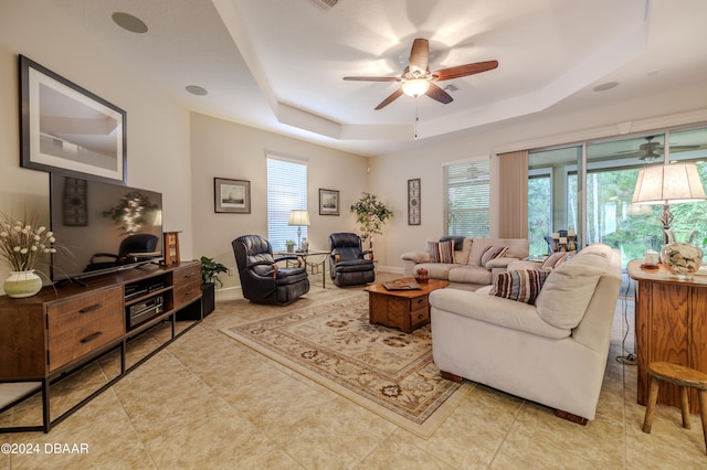 tiled living room featuring ceiling fan and a raised ceiling