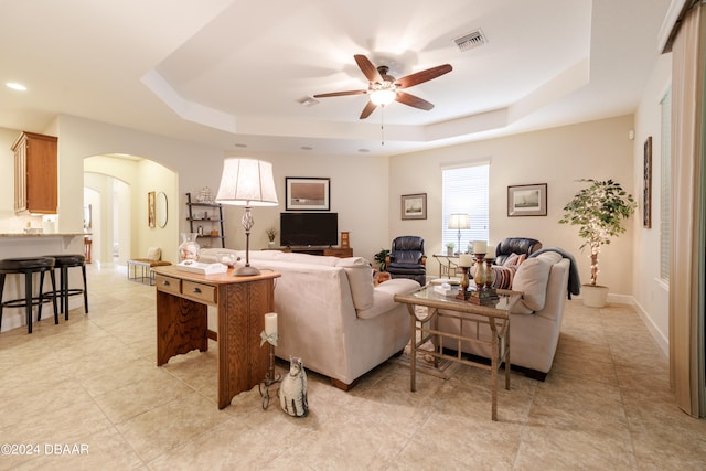 living room featuring a tray ceiling and ceiling fan