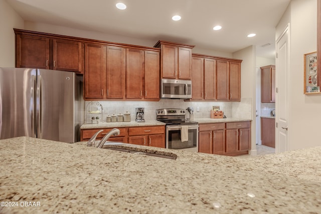 kitchen with tasteful backsplash, light stone countertops, sink, and stainless steel appliances