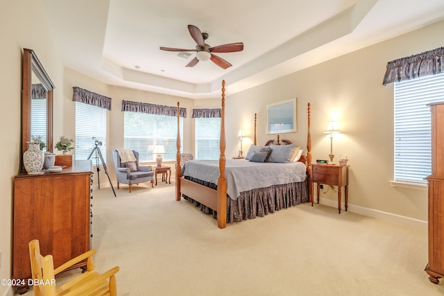 carpeted bedroom with ceiling fan and a tray ceiling