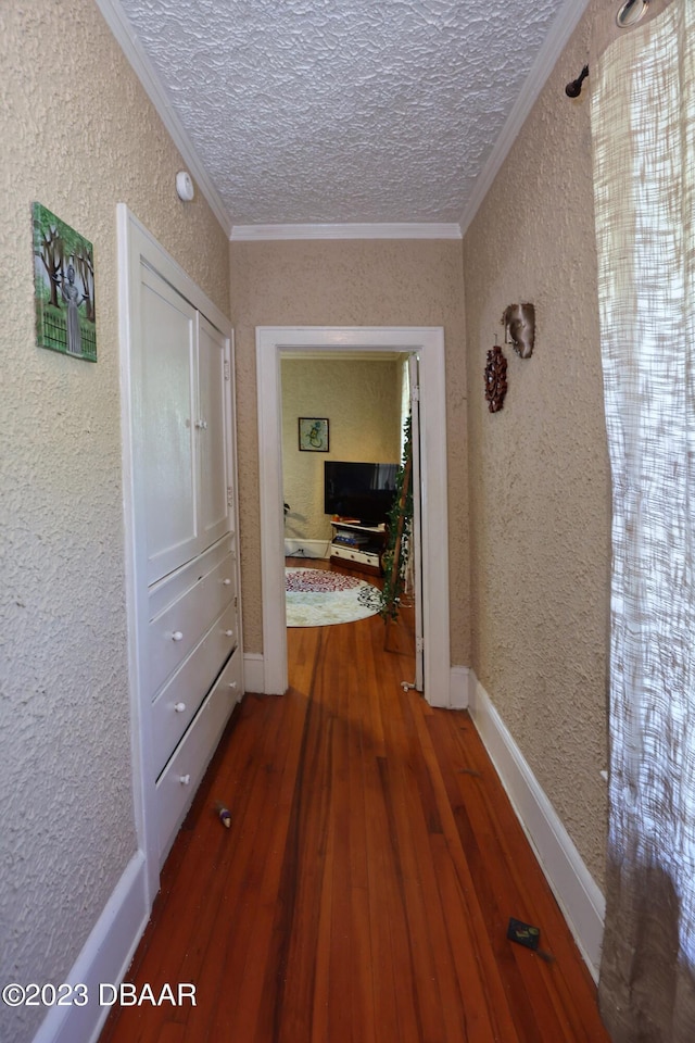 corridor featuring hardwood / wood-style floors, a textured ceiling, and ornamental molding