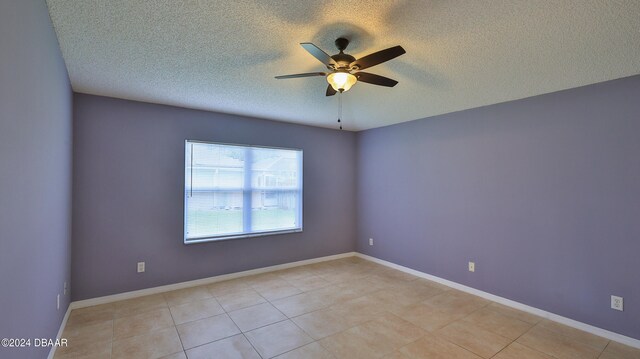 tiled spare room with a textured ceiling and ceiling fan