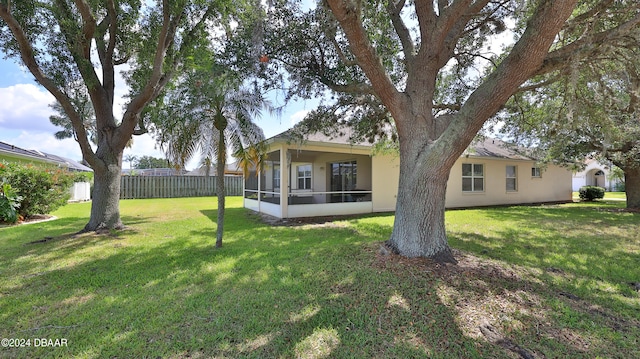 rear view of house featuring a lawn and a sunroom