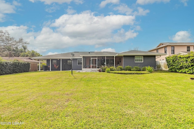 back of house featuring fence, a lawn, and a sunroom