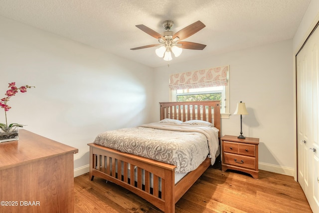 bedroom with baseboards, a closet, light wood-style floors, and a textured ceiling