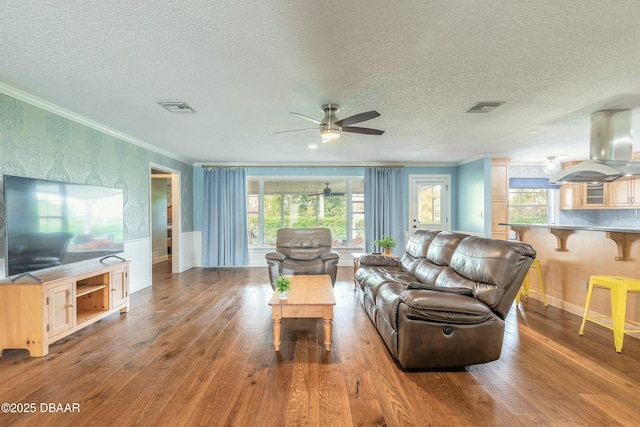 living area featuring crown molding, visible vents, and light wood-type flooring