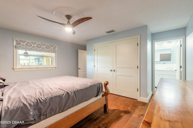 bedroom featuring ceiling fan, visible vents, wood finished floors, a textured ceiling, and a closet