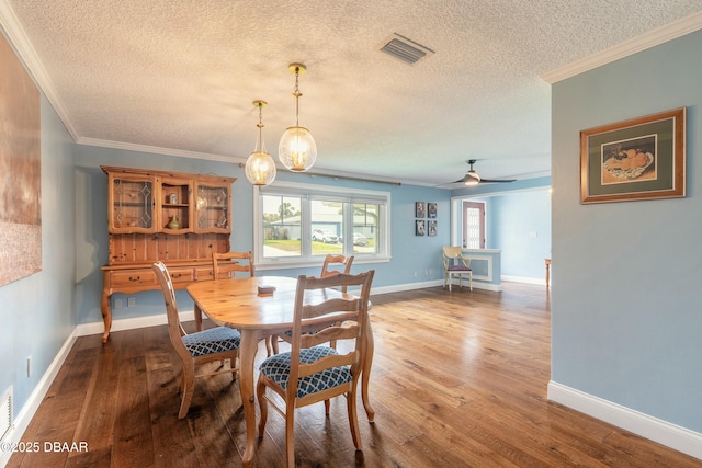 dining space with baseboards, crown molding, and wood finished floors