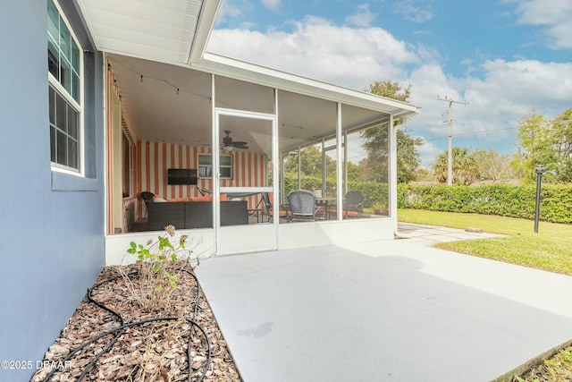 view of patio featuring a ceiling fan and a sunroom