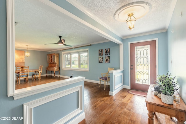 entryway with wood finished floors, crown molding, baseboards, ceiling fan with notable chandelier, and a textured ceiling