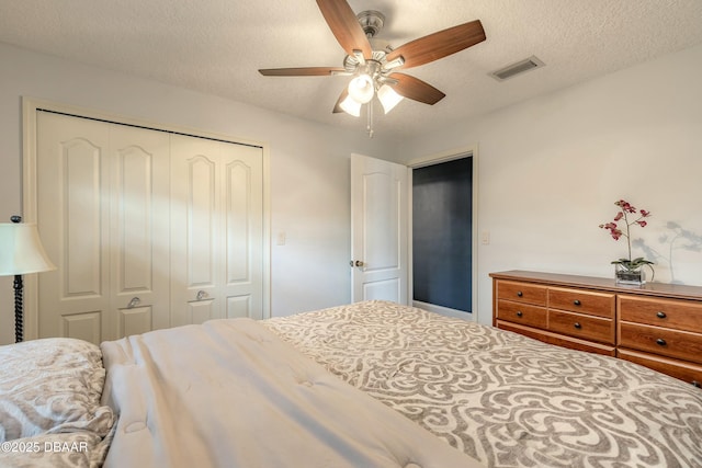 bedroom featuring visible vents, a closet, a textured ceiling, and ceiling fan
