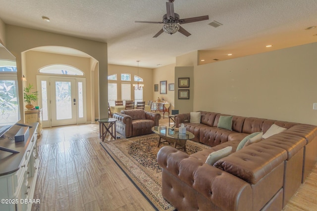 living room featuring ceiling fan, light hardwood / wood-style flooring, and a textured ceiling