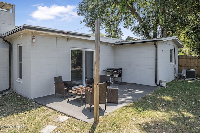 back of property with central air condition unit, concrete block siding, a yard, and a patio