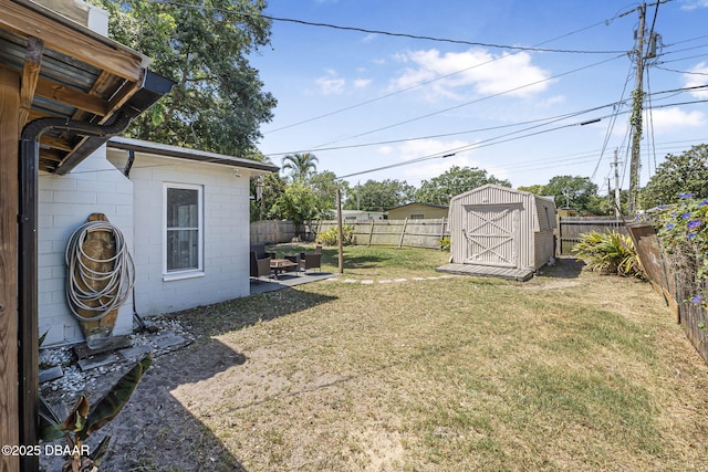 view of yard with a storage unit, a patio area, an outbuilding, and a fenced backyard