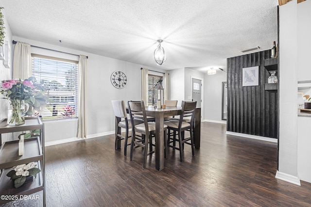 dining area featuring wood finished floors, a textured ceiling, and a healthy amount of sunlight
